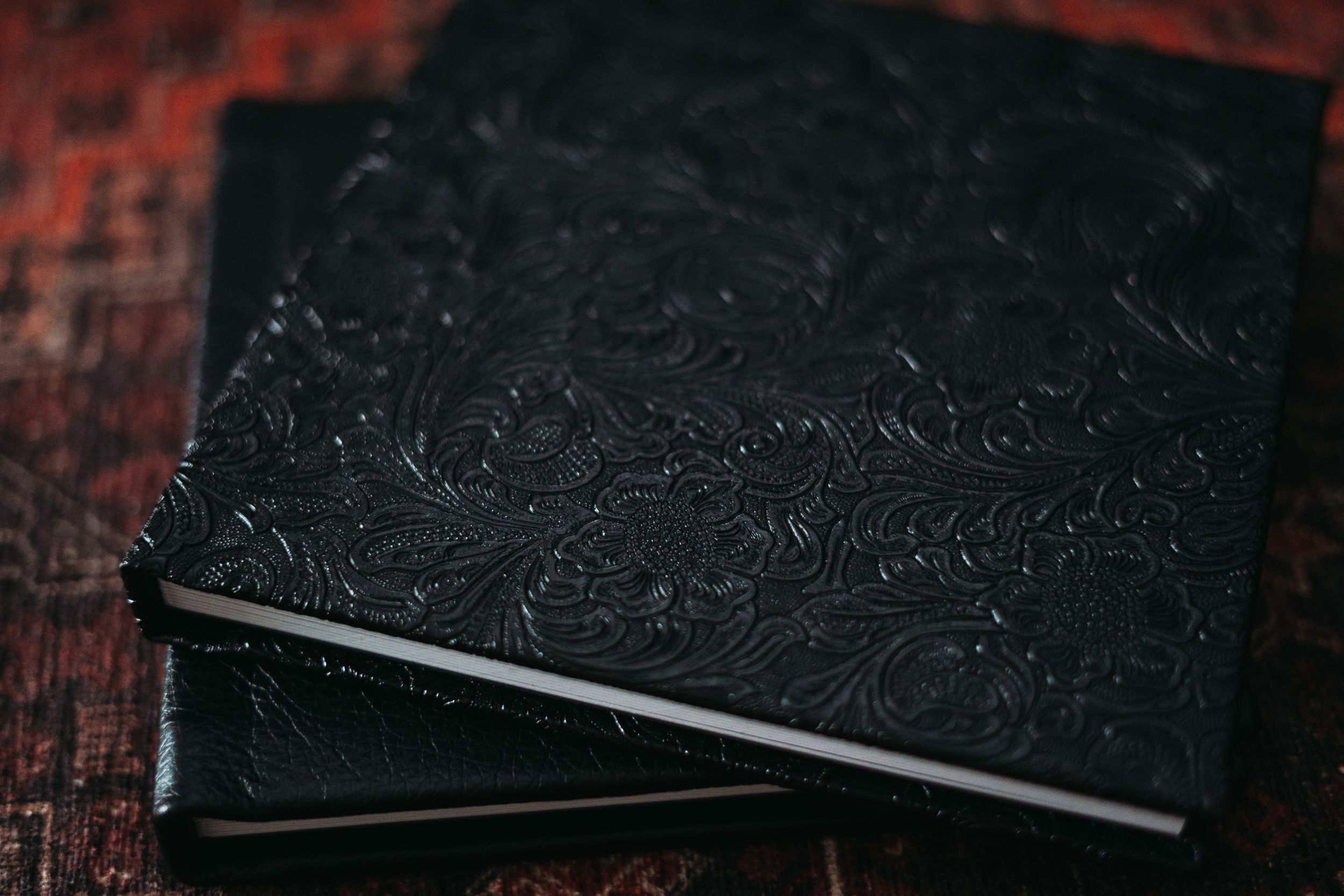 Black leather album with ornate embossed floral pattern detail on cover.