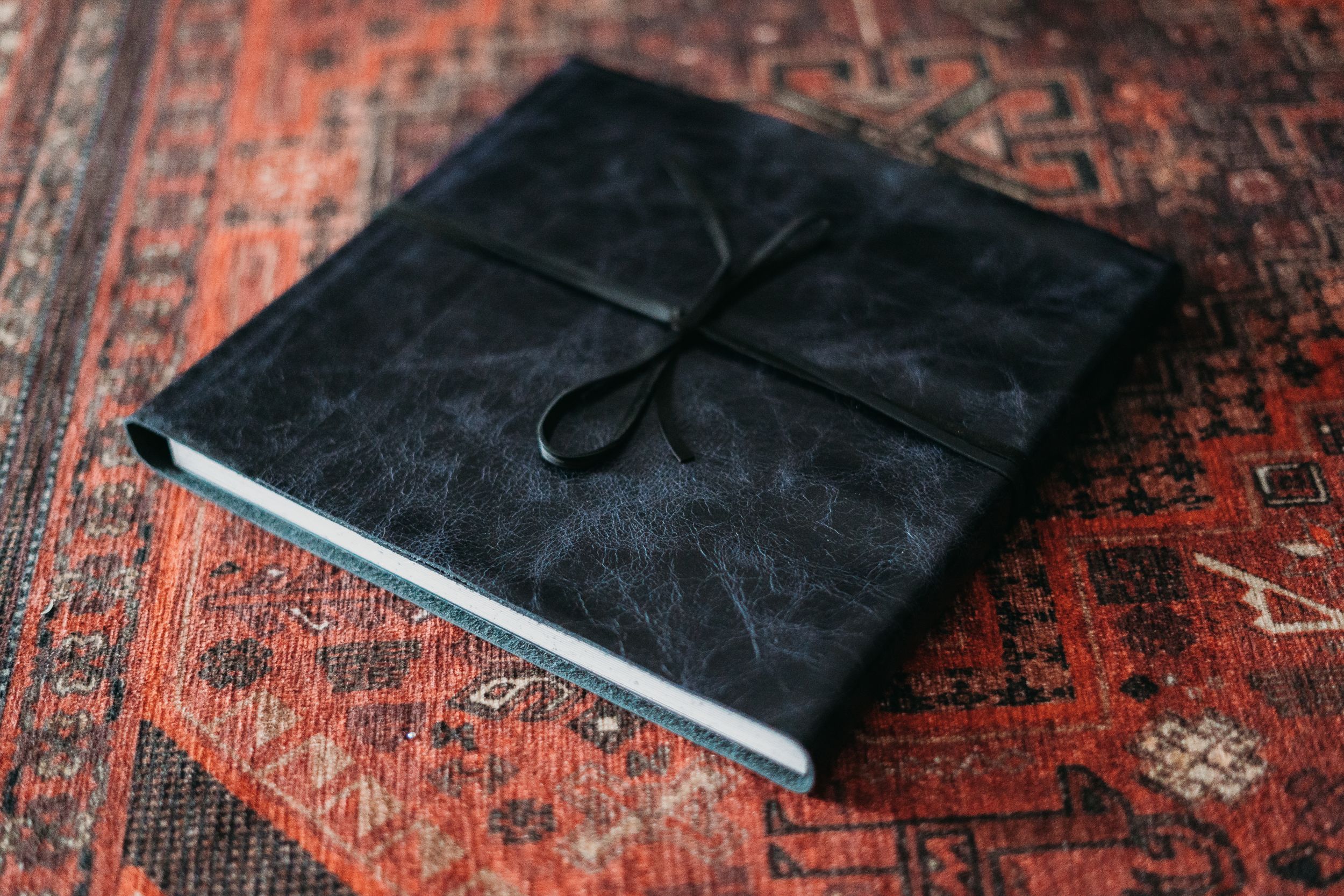 Black leather bound photo album on vintage oriental rug.