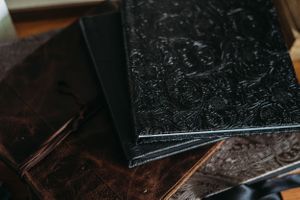 Close-up of embossed black leather photo album covers stacked together.