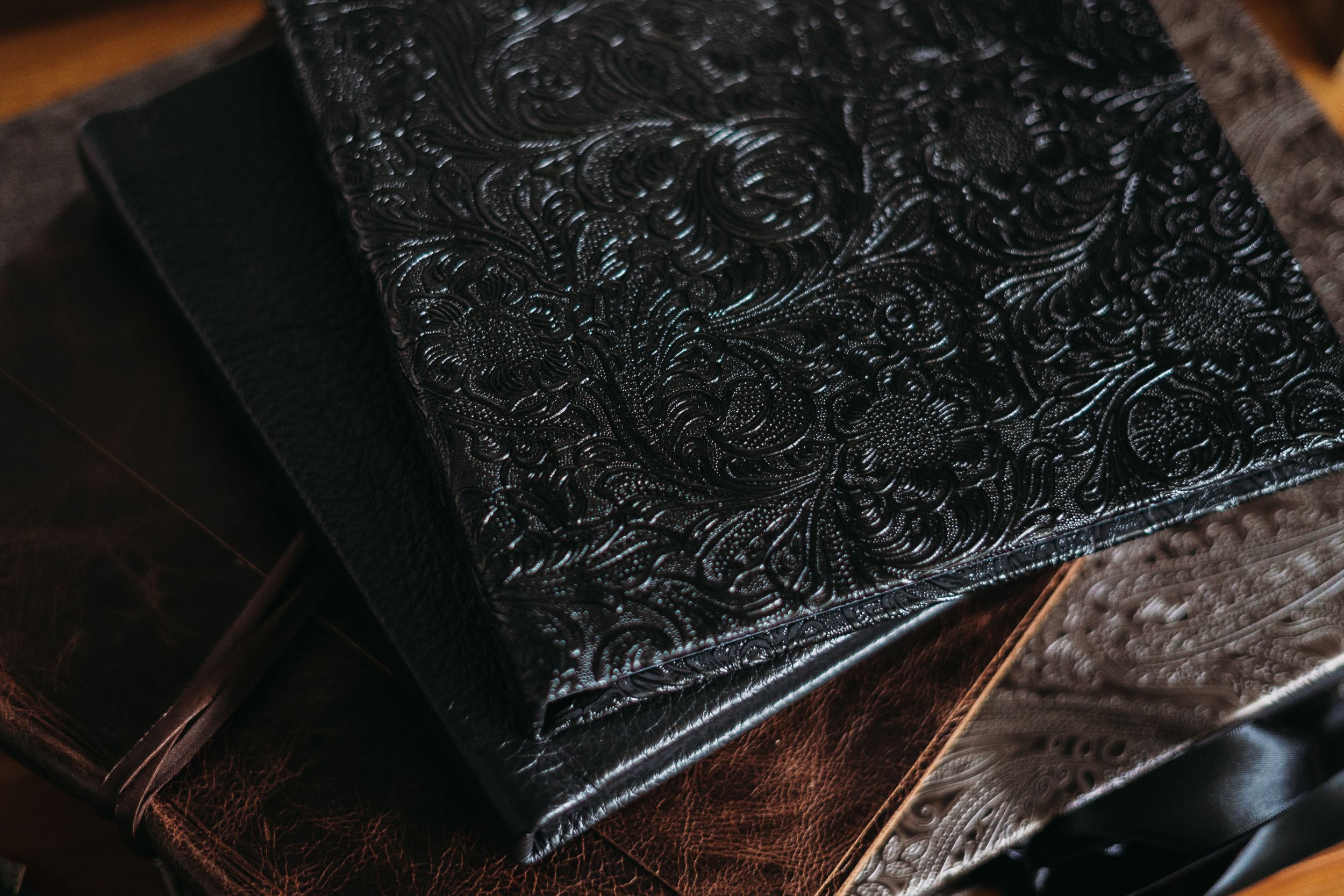 Detailed view of black embossed leather album cover with intricate pattern.