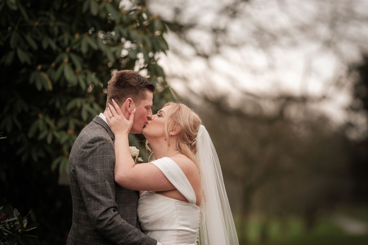 An intimate wedding portrait captured among garden foliage with soft natural lighting.