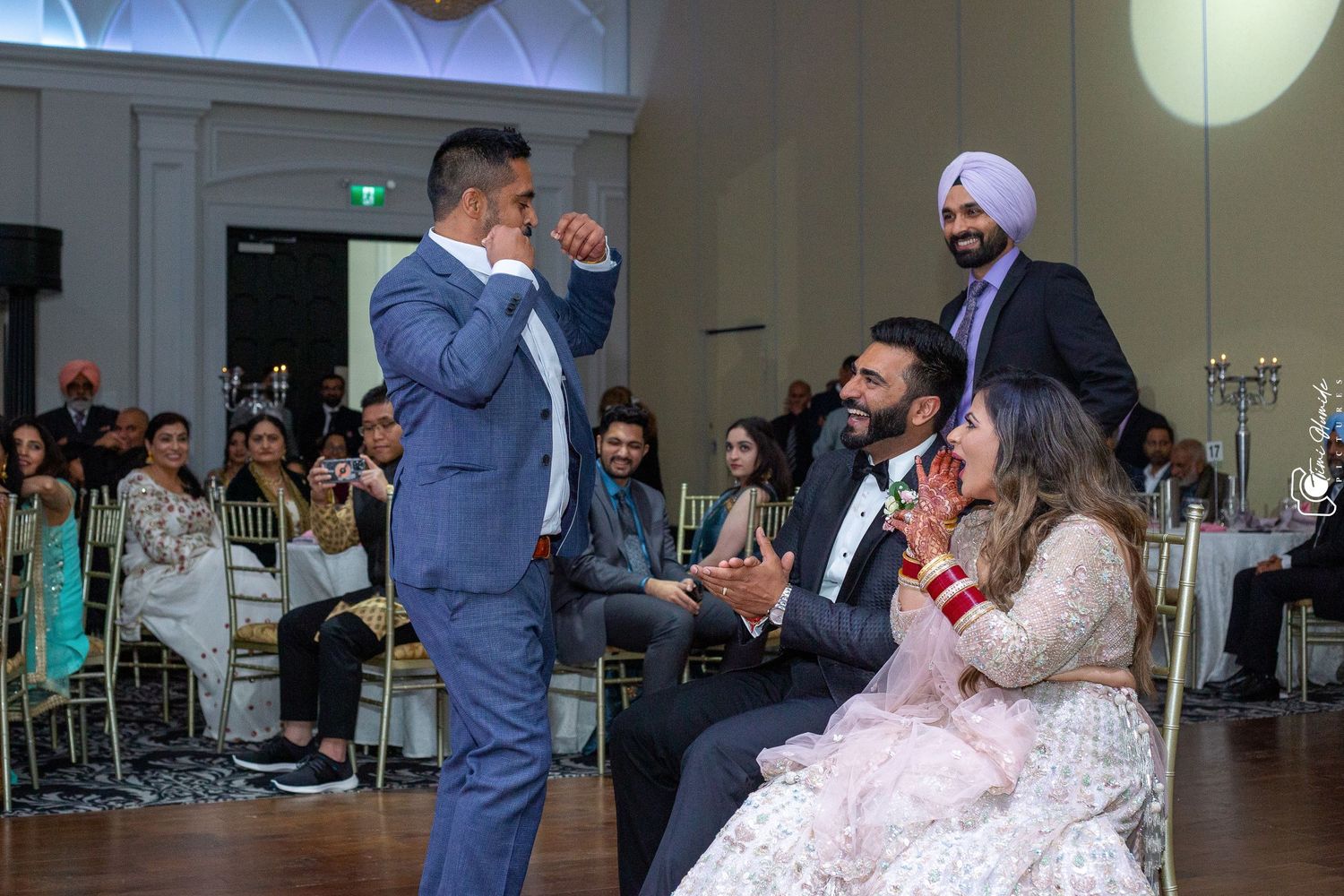 Wedding reception scene with guests gathered in elegant ballroom during speech.