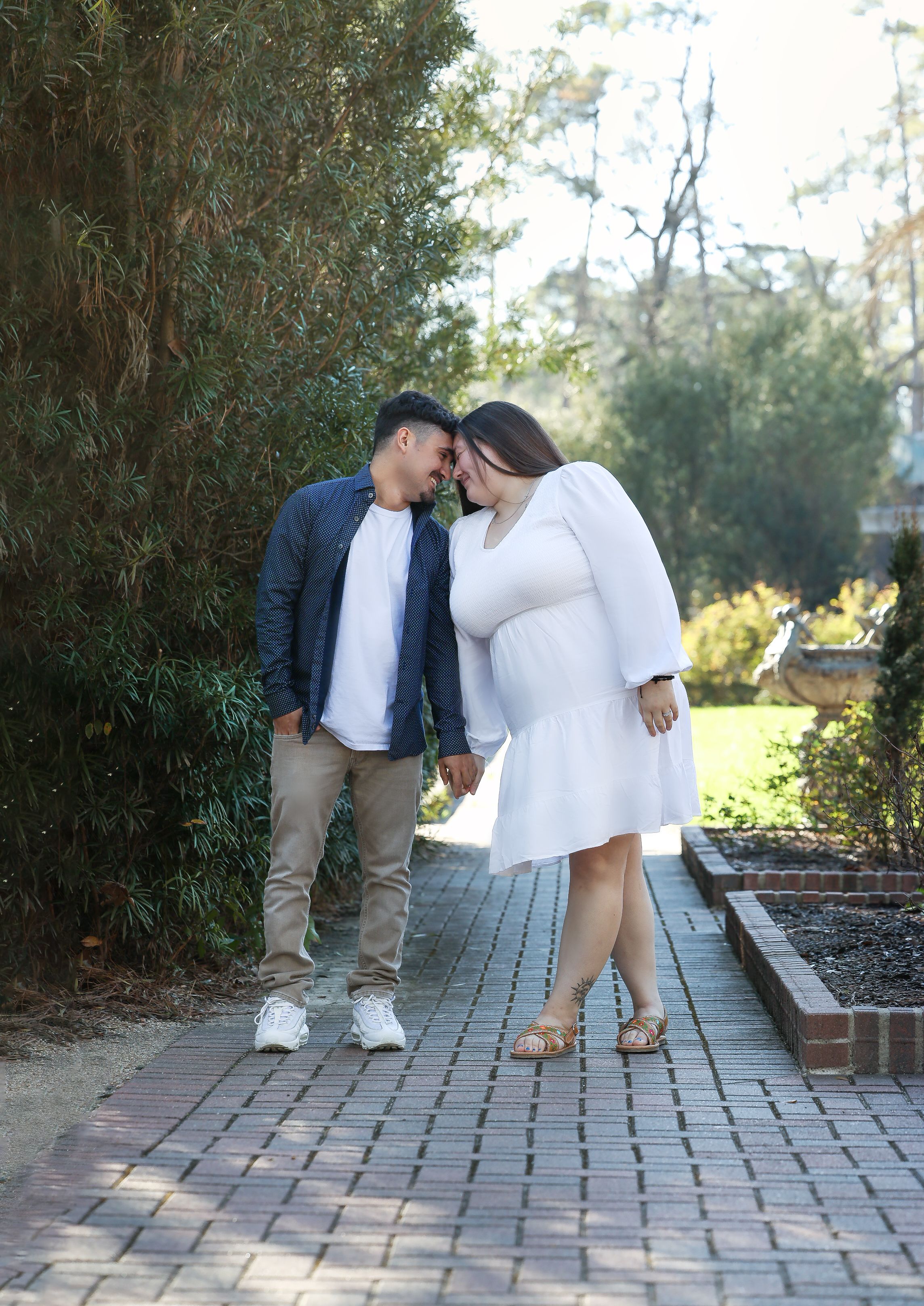 Romantic couple embracing on brick pathway surrounded by greenery.