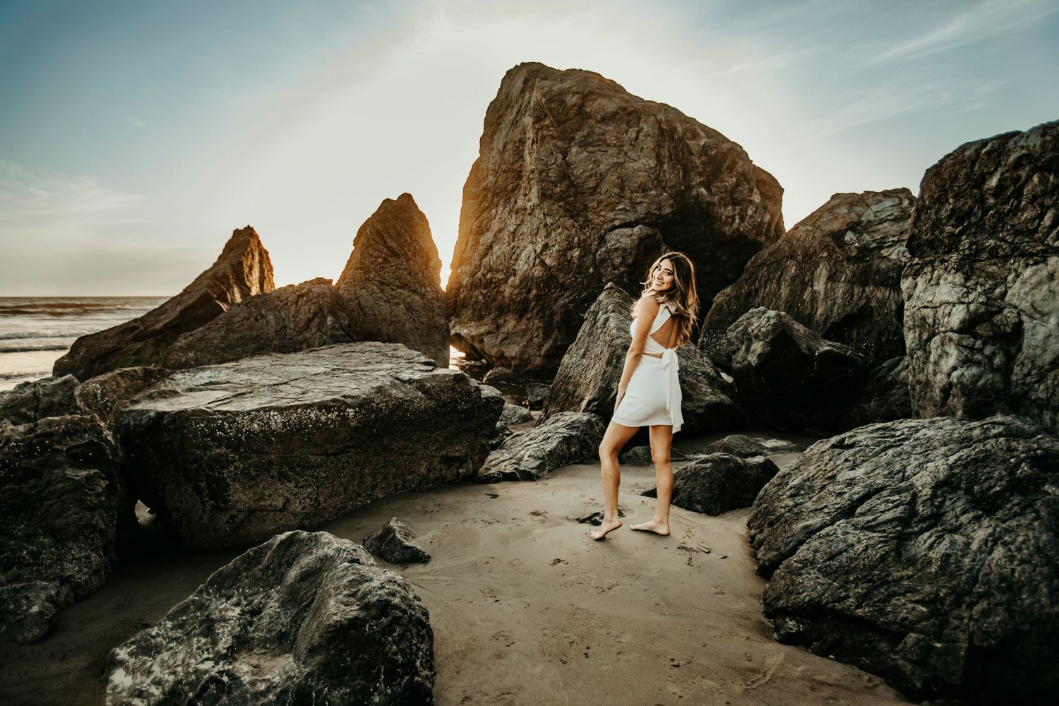 senior portrait on beach with large rocks