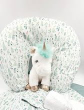 Delicate floral print nursing pillow with green accents and ribbon details on white background.