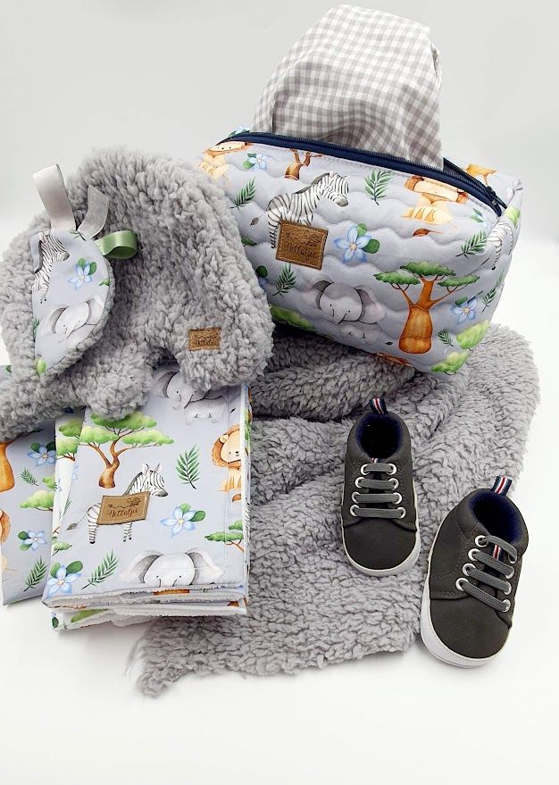 Animal print baby bag set with plush elephant toy, blanket, and gray baby shoes.