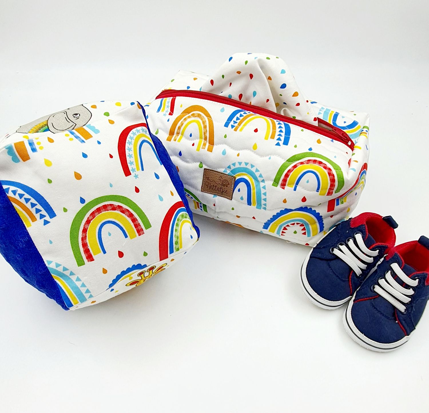 Rainbow patterned baby wipes package shown with blue baby shoes and accessories.