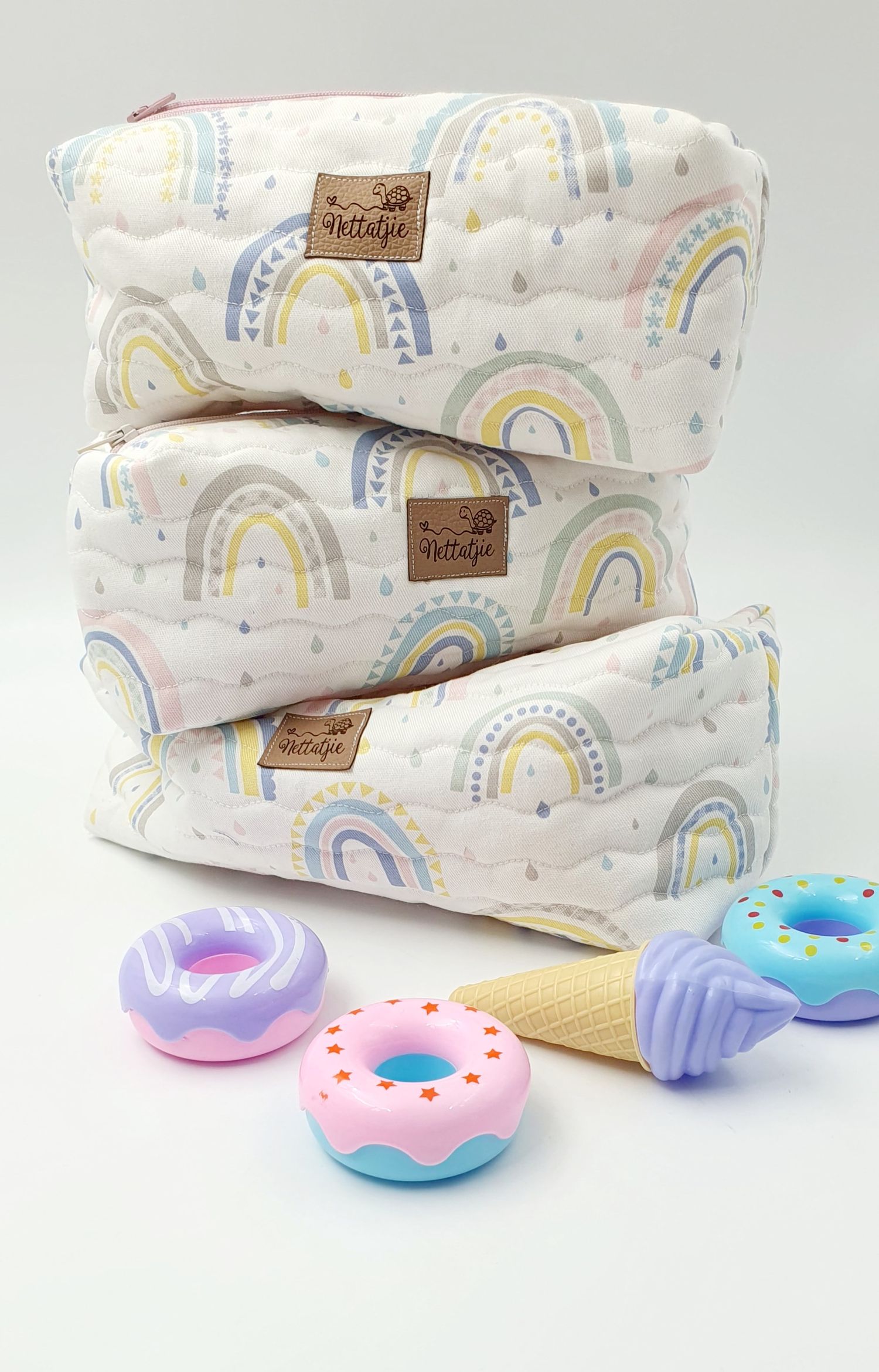 White rainbow pattern baby wipes with colorful donut-shaped teething toys.