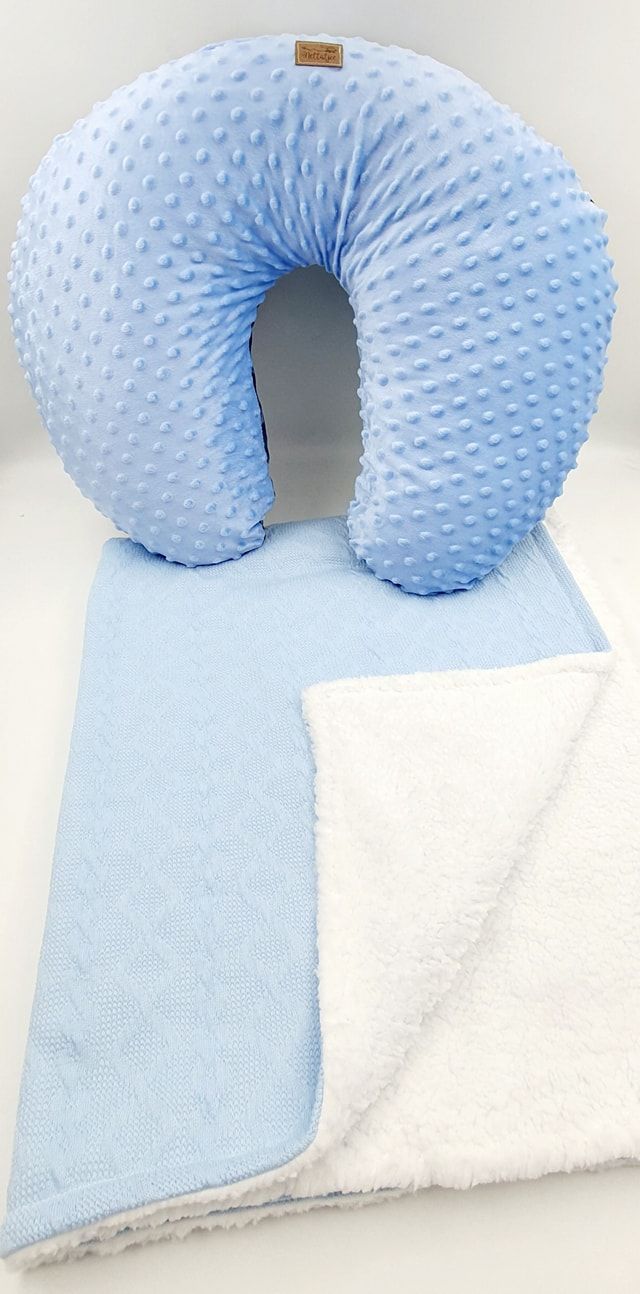Light blue minky nursing pillow with textured dots displayed on soft white blanket.