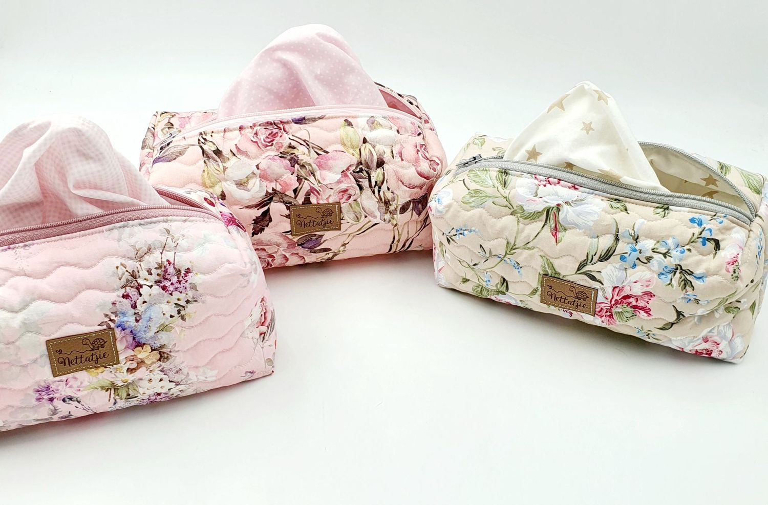 Collection of delicate pink and white floral print cosmetic bags arranged in a row.