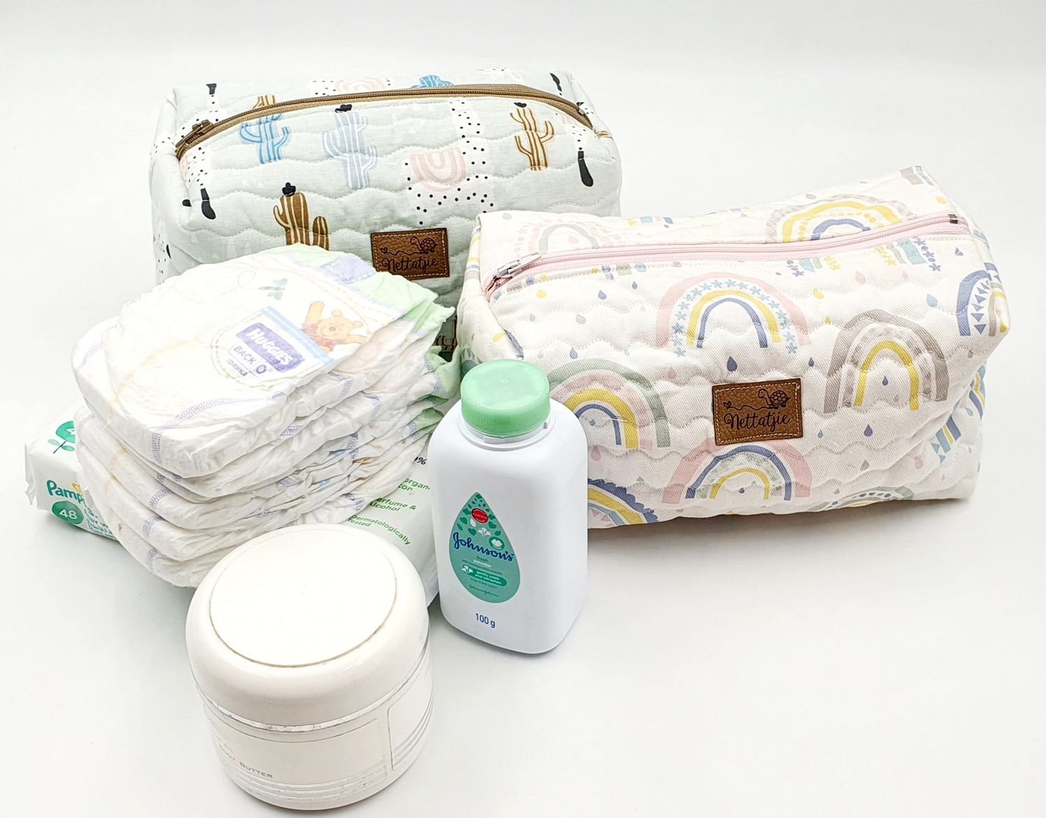 Baby care set with rainbow print diaper bag, diapers, and toiletry items.