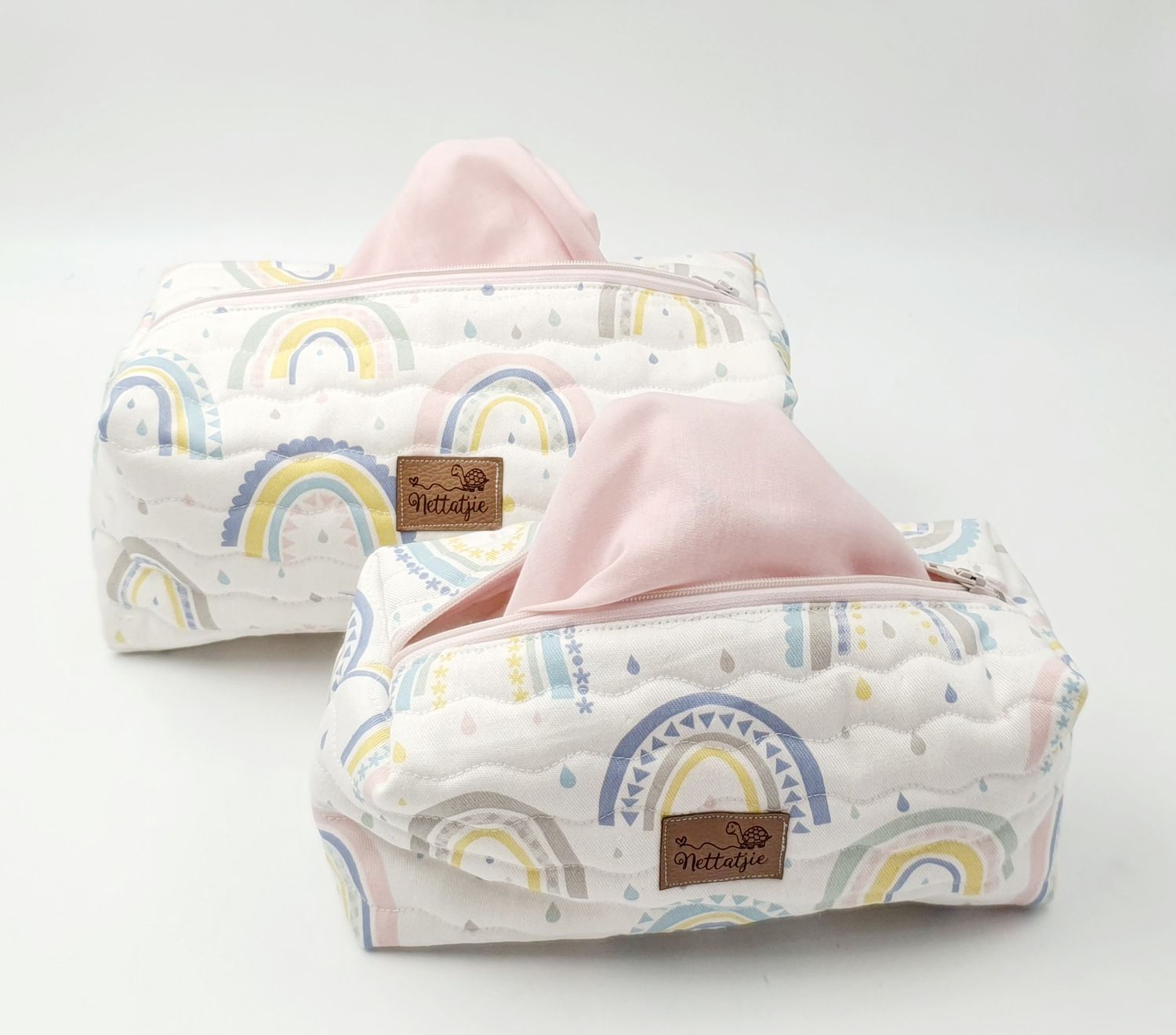 Pastel rainbow patterned baby wipes cases stacked together on white background.