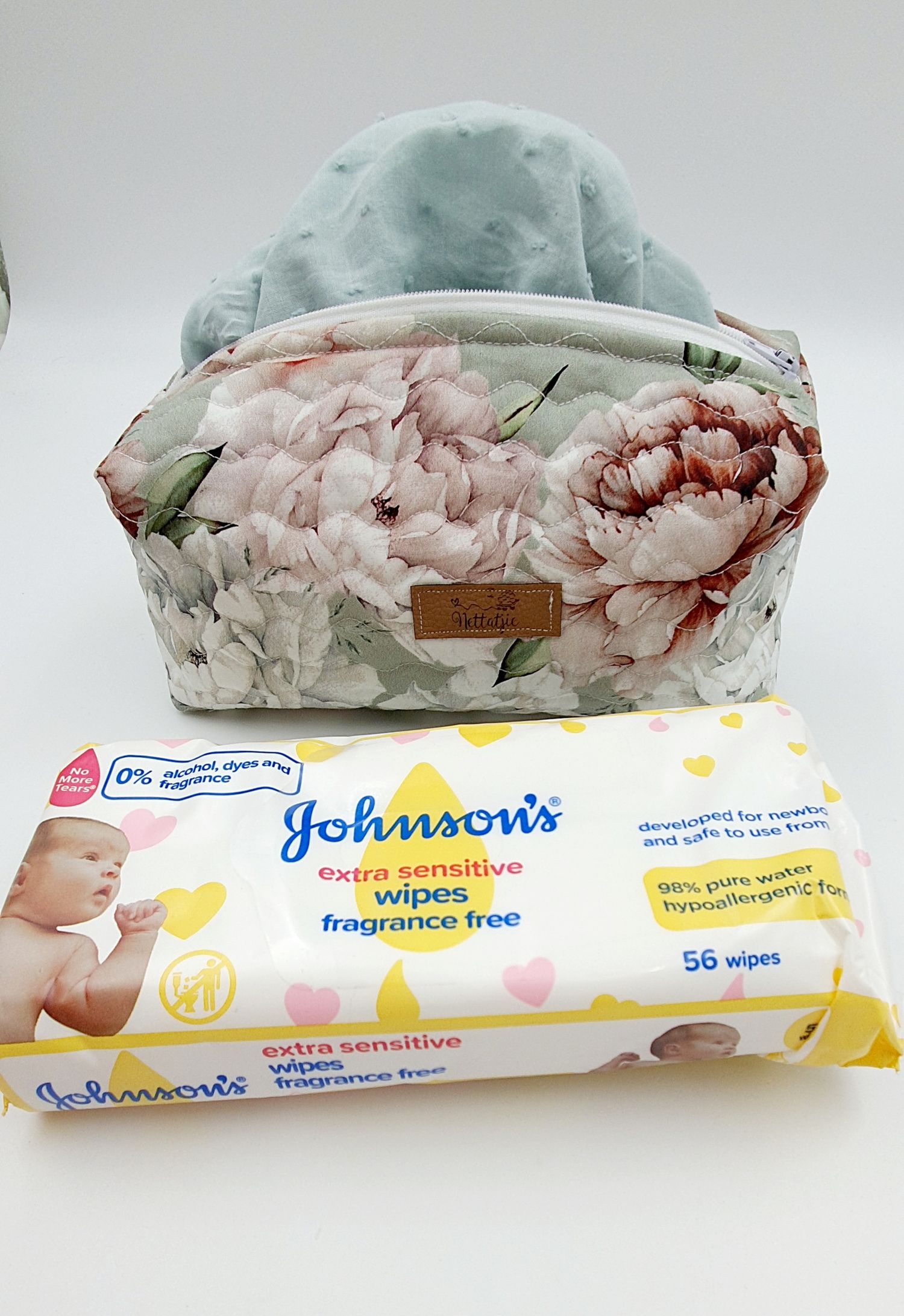 Floral print cosmetic bag with mint minky fabric top displayed with Johnson's baby wipes package.