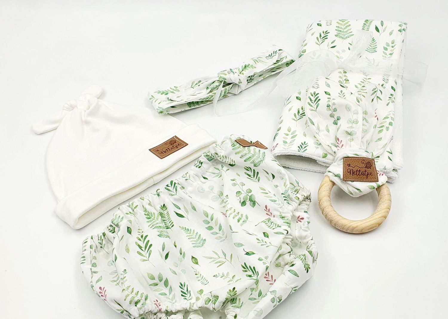 Delicate green floral print baby accessories on white background.