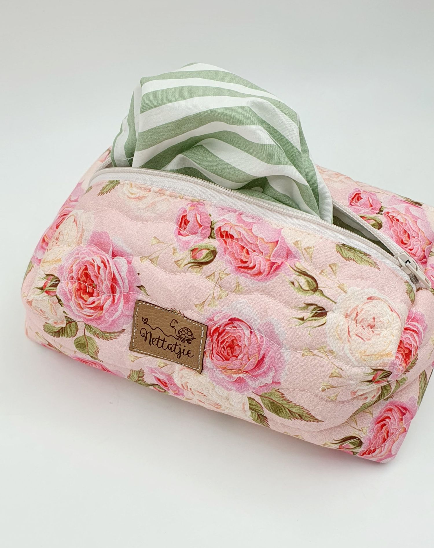 Pink floral cosmetic bag with green striped handle featuring vintage rose print pattern and leather label.