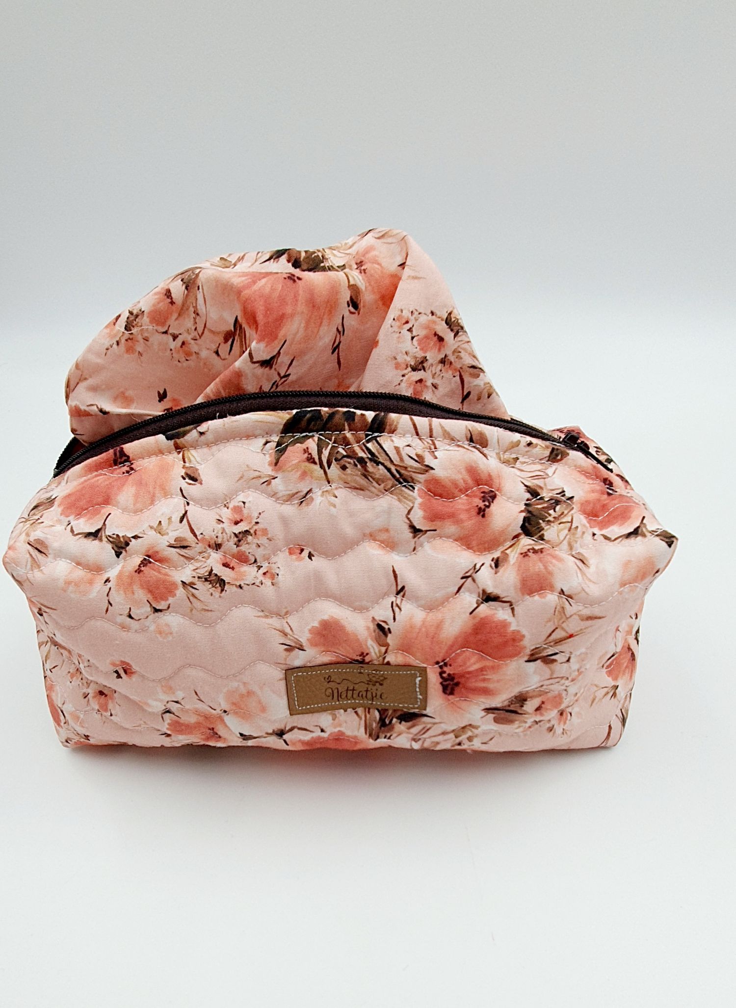 Coral watercolor floral print cosmetic pouch with black trim and zipper closure.