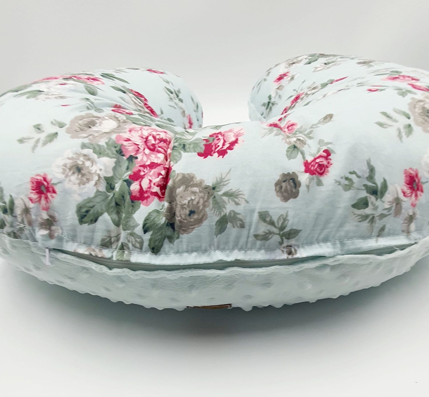 Close-up of nursing pillow with romantic rose print pattern.