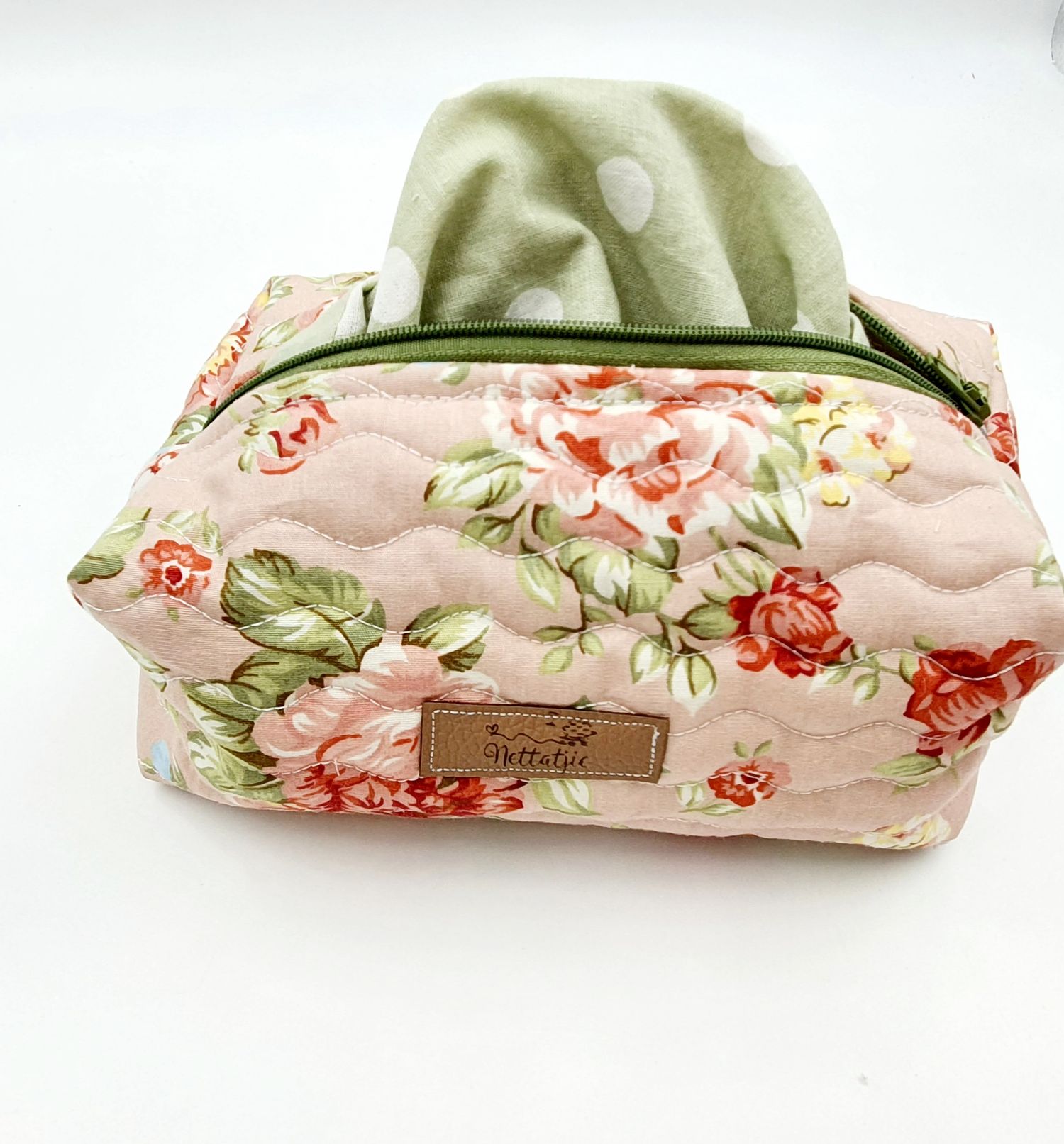 Floral print toiletry bag with pink roses and green leaves on cream background featuring tissue dispenser.