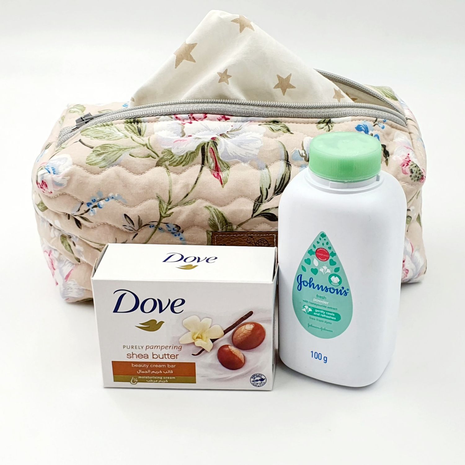 Star-patterned toiletry bag with floral accents displayed with Dove soap and baby powder.