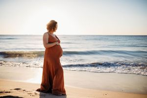 a mum to be cradling her baby bump at sunset during a photoshoot with India Foxx Photography.