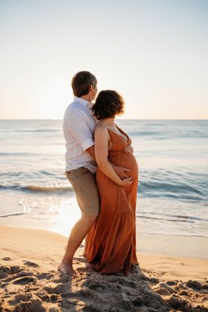 a couple embracing on the beach during a photoshoot with India Foxx photographer, a maternity photographer based in Shrewsbury.