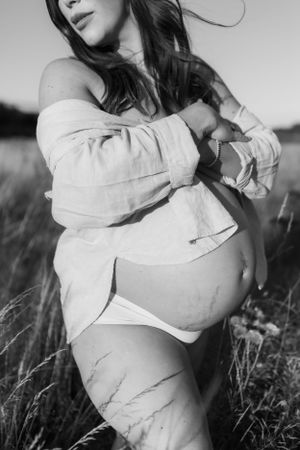 semi nude maternity photoshoot in full sun on a summers evening in a field in Shrewsbury shot by India Foxx Photography.