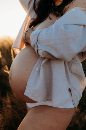 semi nude maternity photoshoot in full sun on a summers evening in a field in Shrewsbury shot by India Foxx Photography.