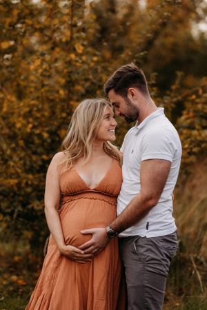 a happy couple outdoors in Shrewsbury at sunset celebrating becoming parents in maternity shoot - photo shot by India foxx photography.