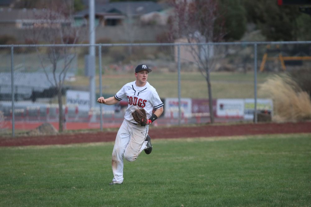 Baseball player sliding into base during game action sequence on grass field.