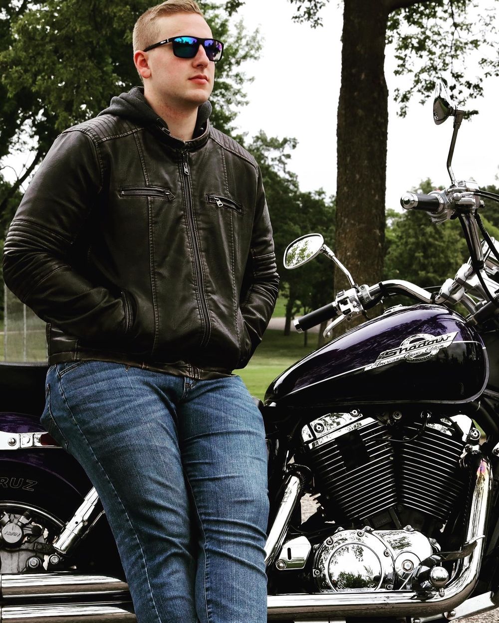 Black motorcycle parked outdoors with rider in leather jacket and jeans.