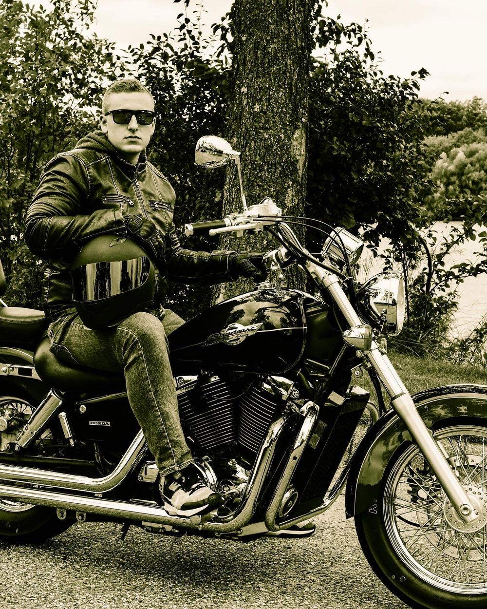 Vintage style black and white photo of motorcycle rider on parked bike.
