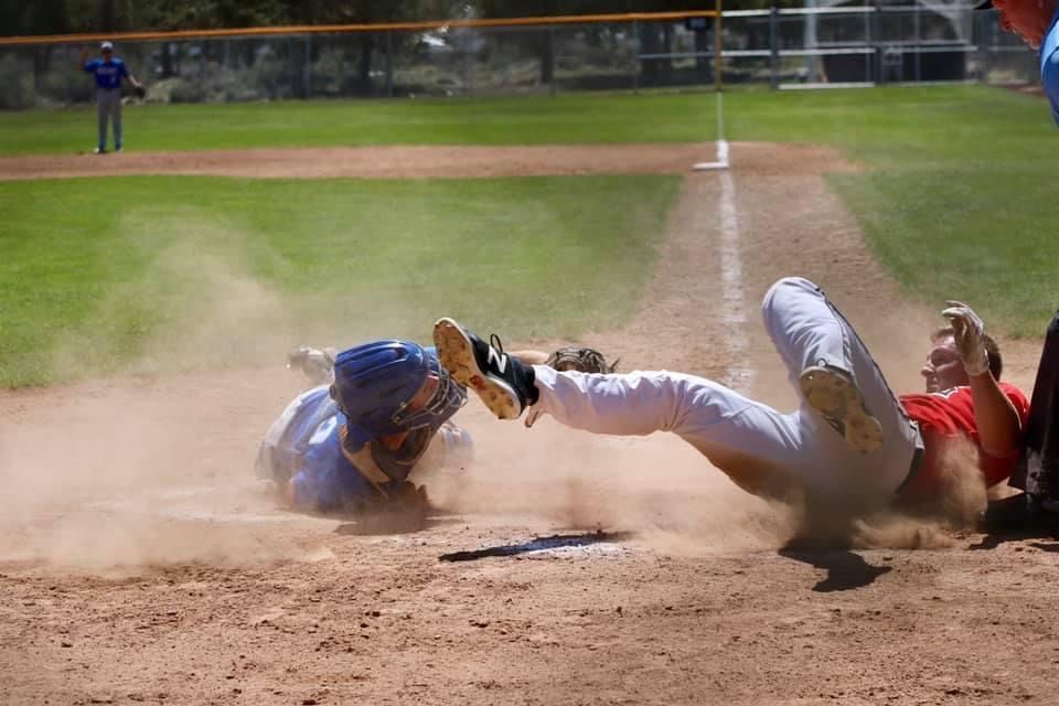 Baseball players creating dust cloud during dramatic play at home plate.
