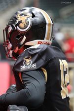 Football player in black uniform and helmet preparing for game action on the field.