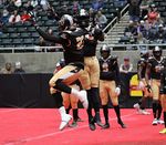 Two football players jumping and celebrating during a game in a stadium.