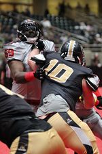 Football players engaged in a blocking play during a competitive game.