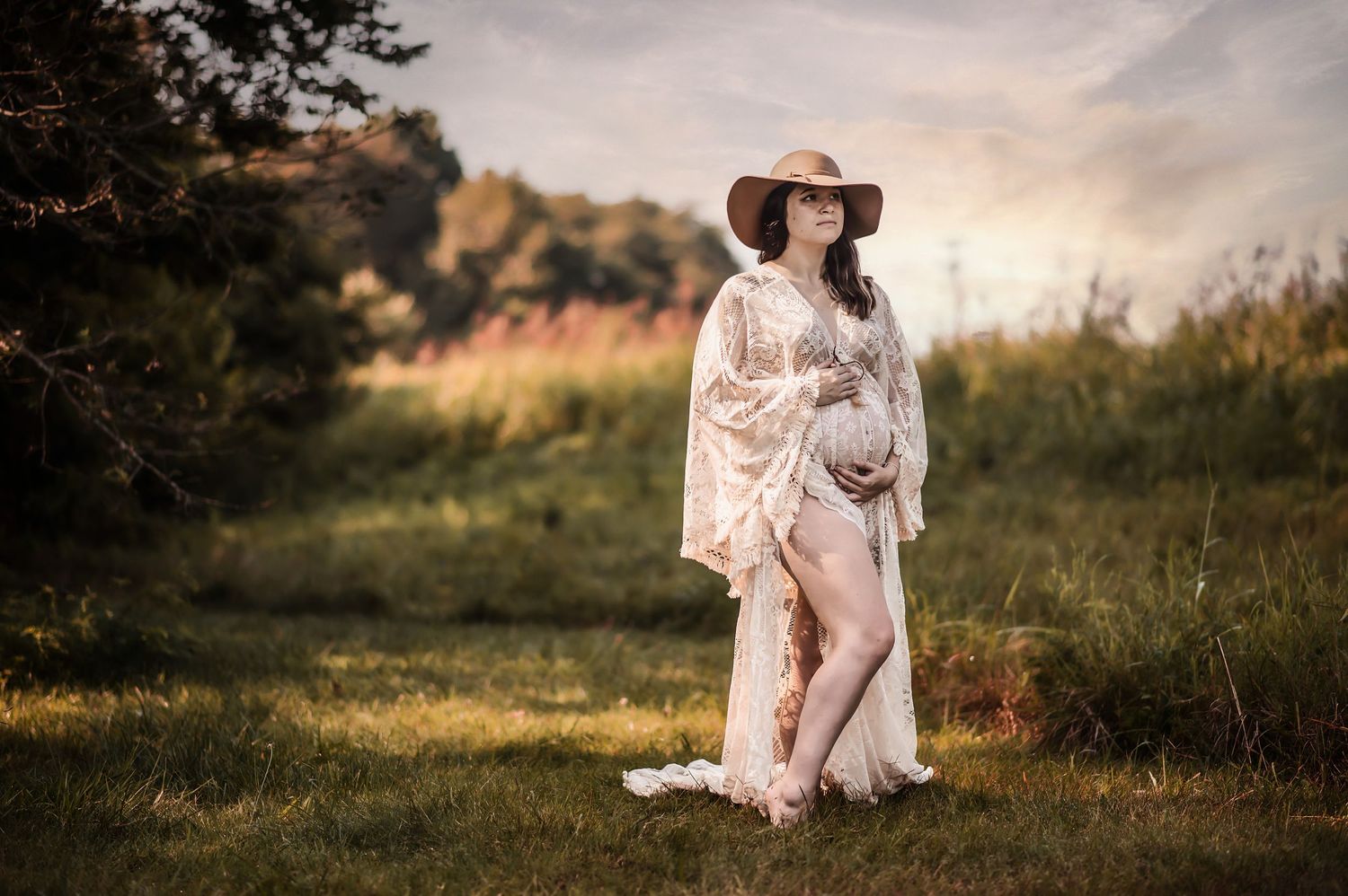Romantic countryside photography session with flowing dress and wide-brimmed hat at golden hour.