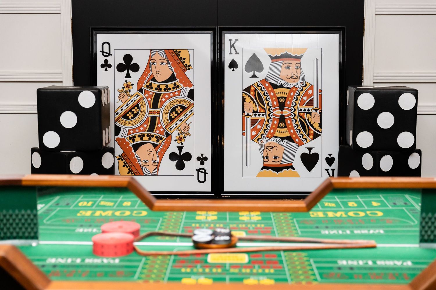 Playing cards and dominoes arranged on green casino table featuring Queen and King of Spades.