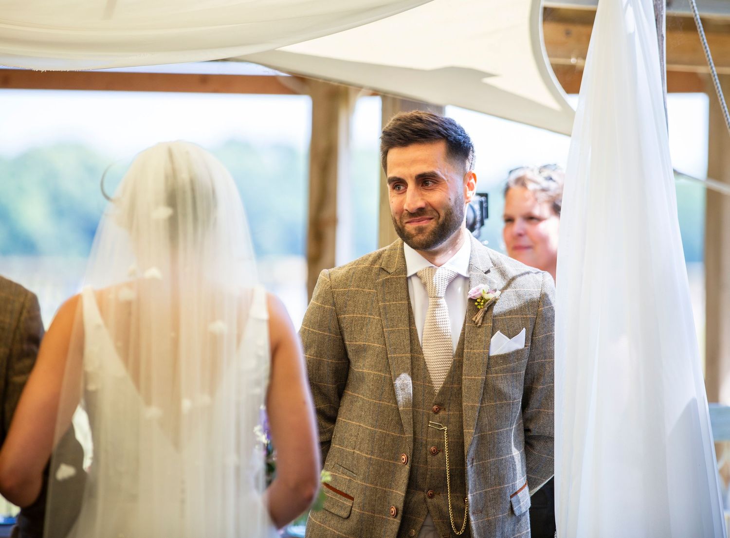 A wedding ceremony moment captured under draped fabric in an indoor venue.