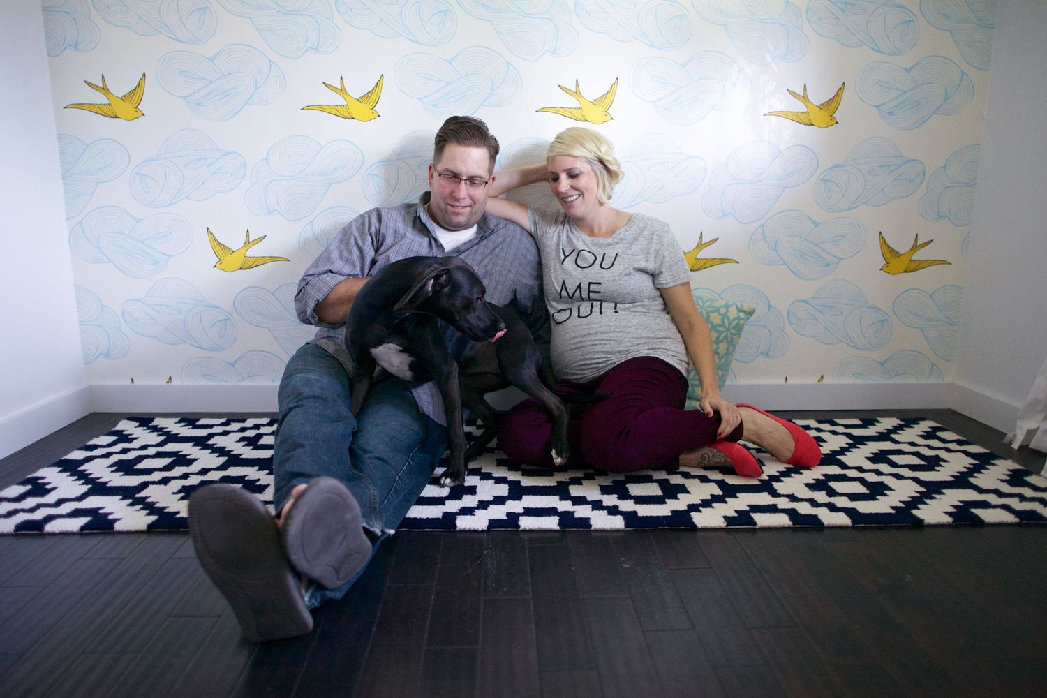 Nursery room with blue walls decorated with yellow bird motifs and geometric floor rug.