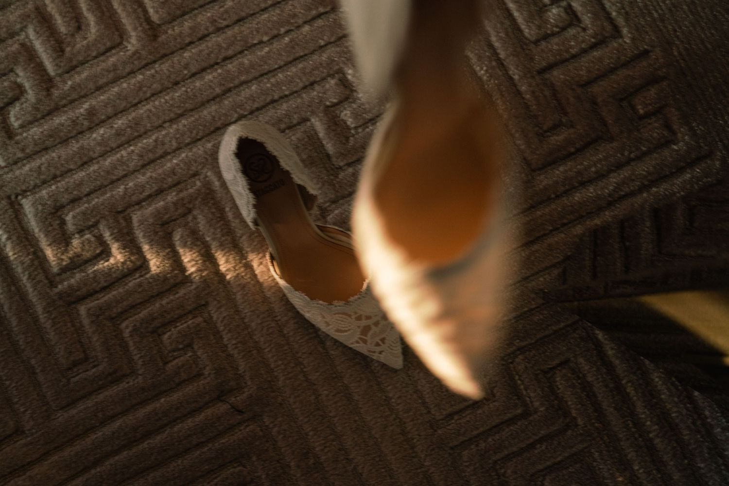 Close-up detail shot of a high heel shoe on textured carpet.