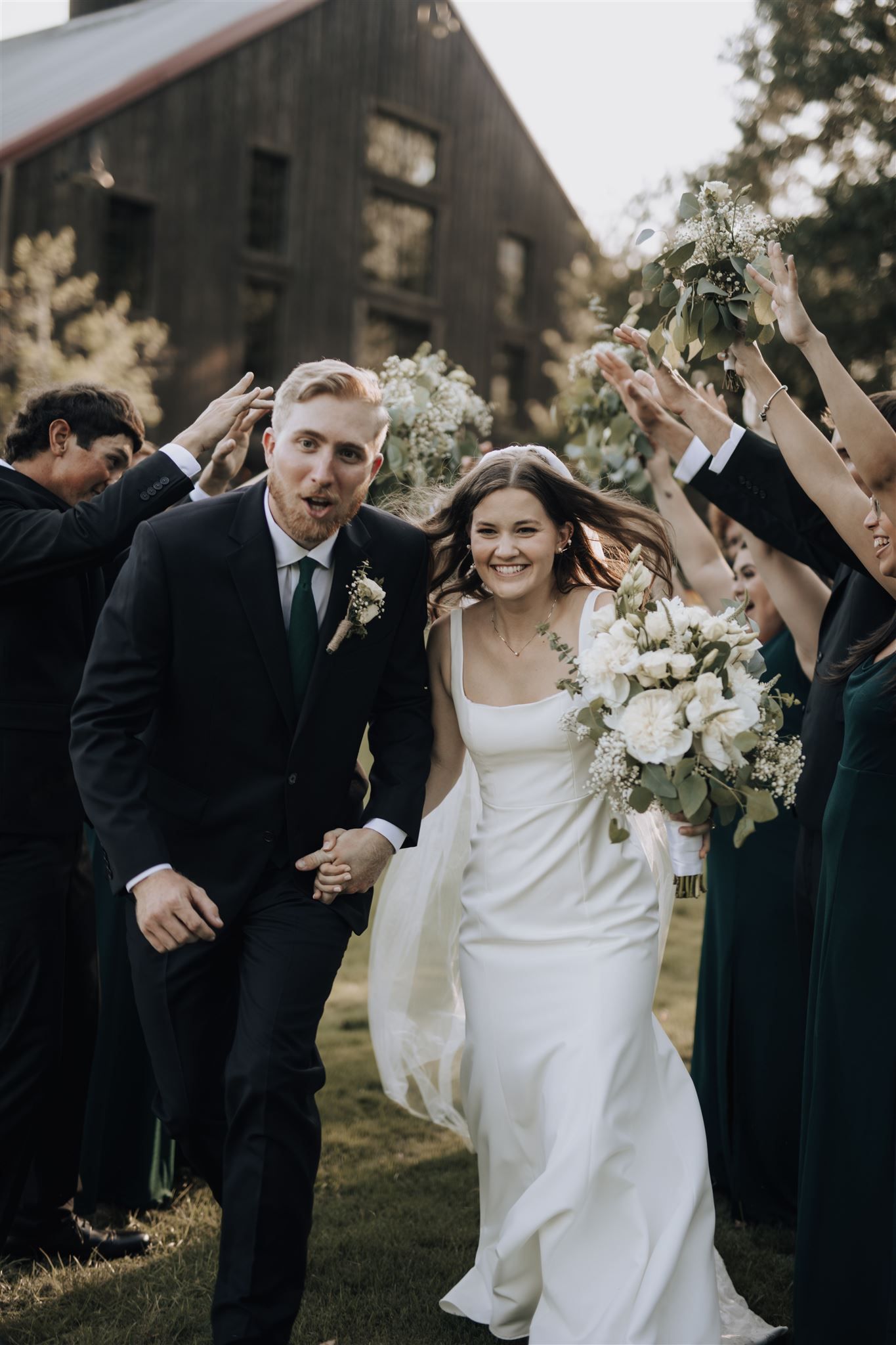 Wedding celebration with guests in dark attire creating celebratory tunnel outdoors.