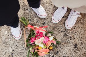 White sneakers and colorful flowers arranged on a stone surface.