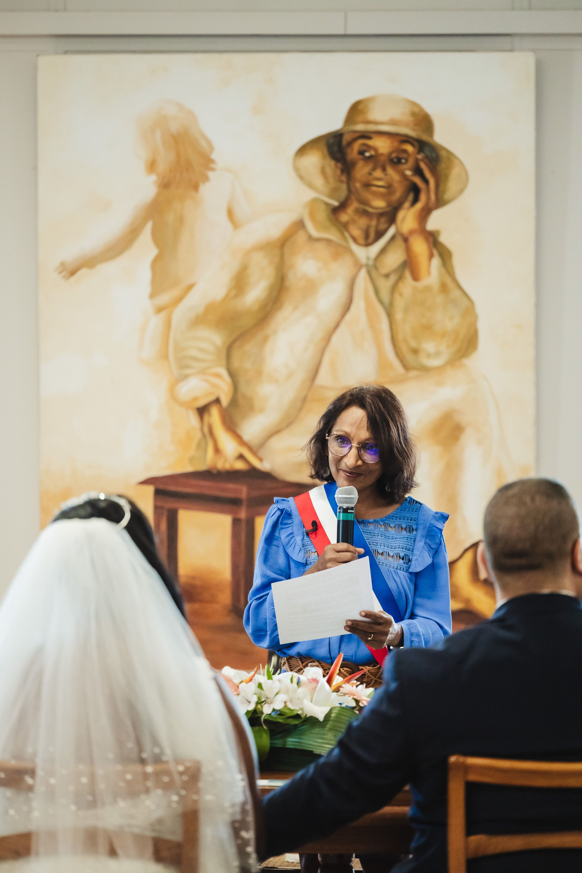 Wedding ceremony in church with guests seated and decorative wall murals.