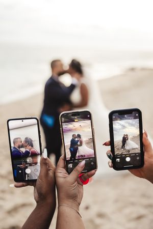 Multiple phones capturing a special moment on the beach.