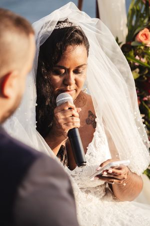 Emotional moments during outdoor wedding ceremony with bride reading vows.