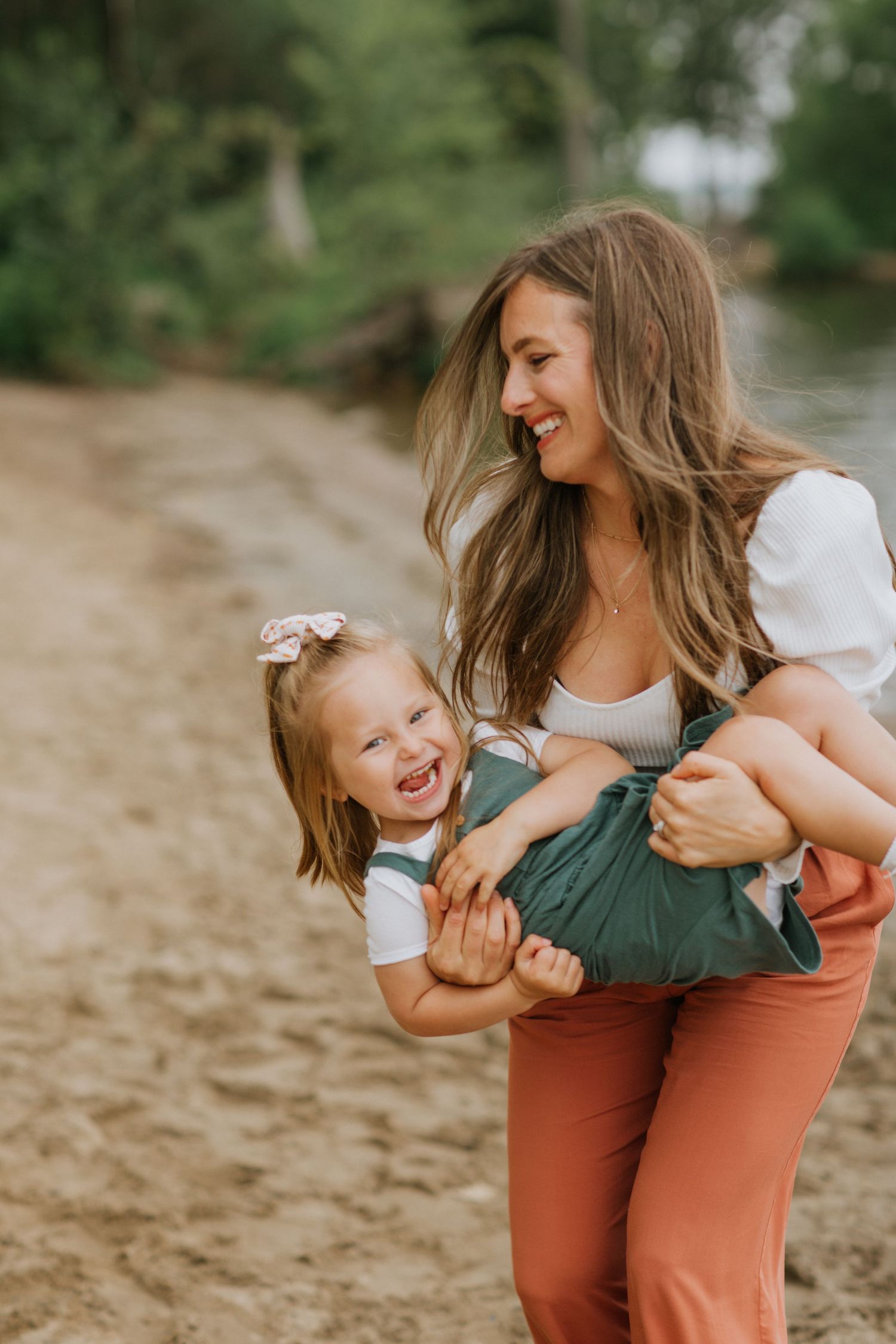 Playful moment between parent and child laughing together on a sandy beach.