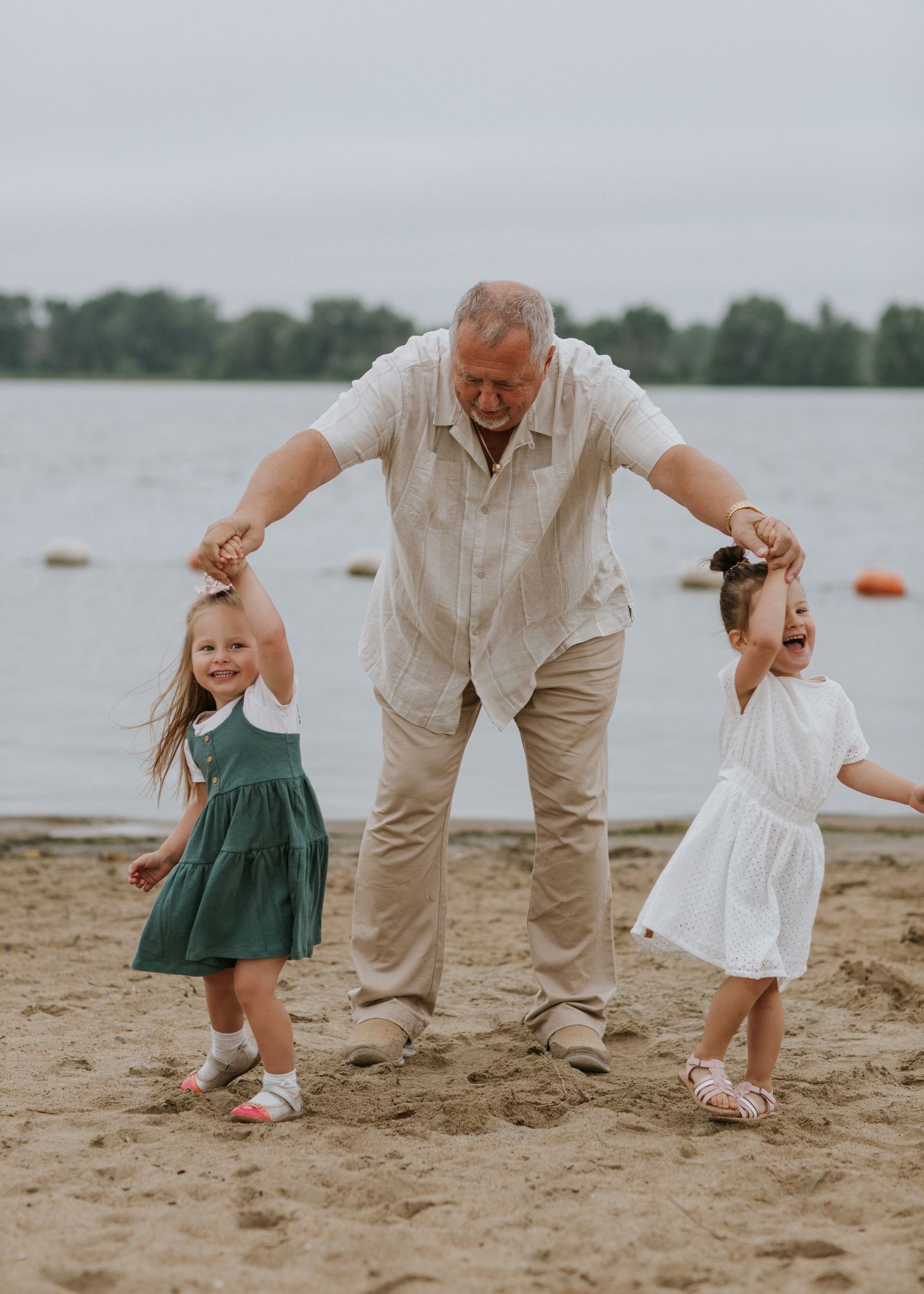Playing and dancing together on a sandy beach by the lake on an overcast day.