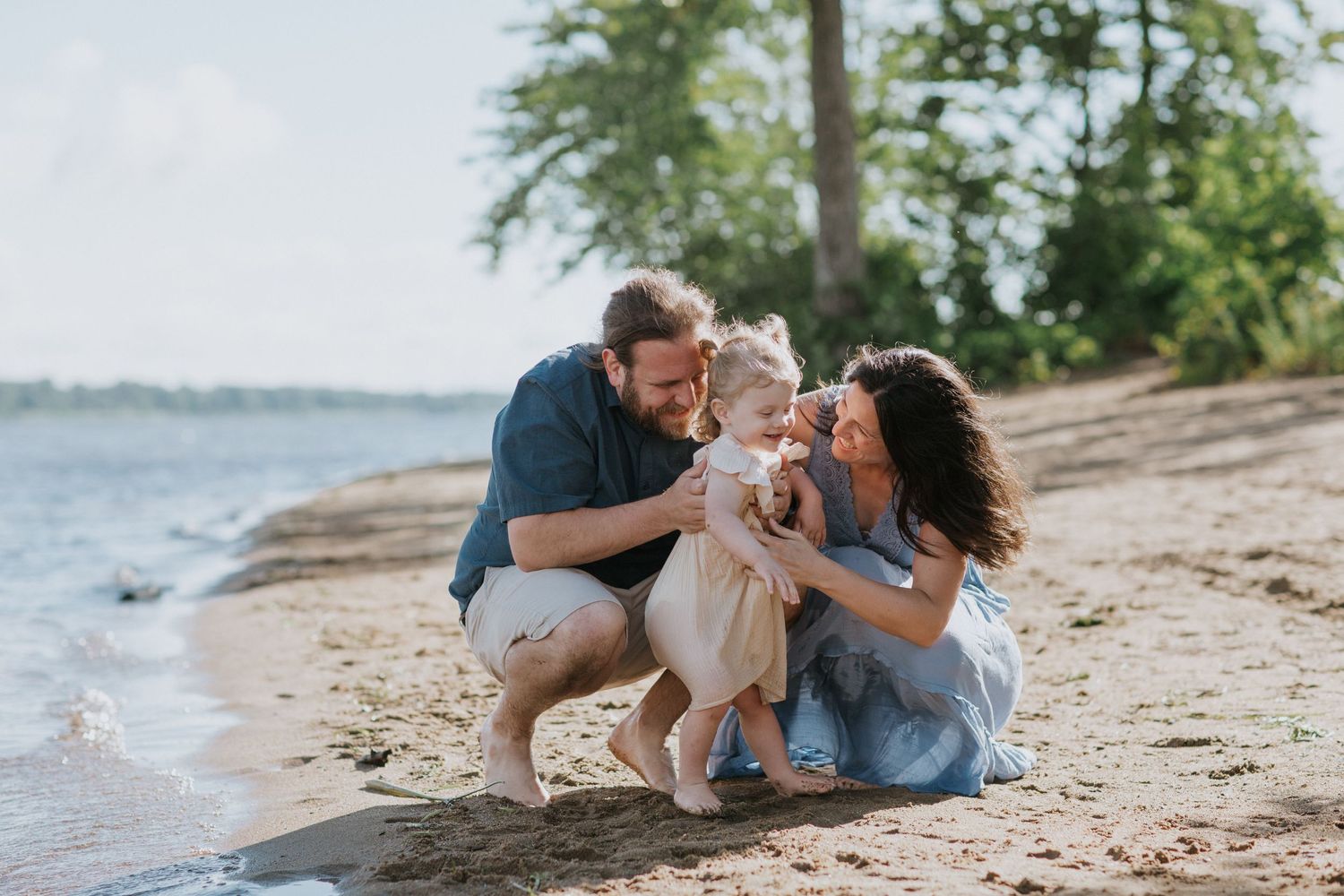 Family enjoying a tender moment together while lying on a sandy beach.
