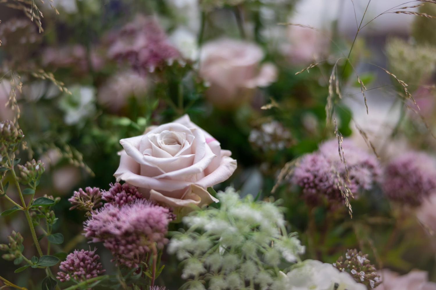 Delicate pink roses and purple flowers arranged in a romantic garden bouquet.