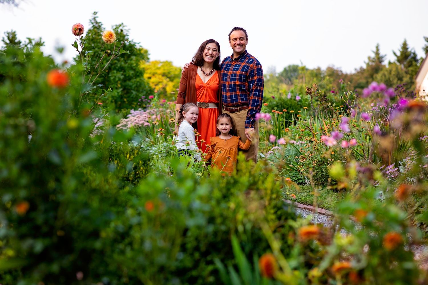 Couple poses together among colorful blooming flowers in vibrant garden landscape.